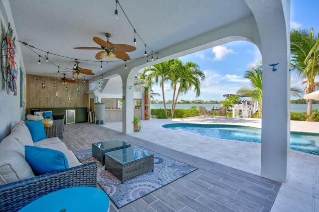 view of swimming pool with a patio area, outdoor lounge area, ceiling fan, and exterior kitchen