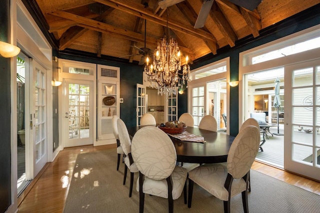 dining space featuring french doors, beamed ceiling, wood finished floors, and a notable chandelier