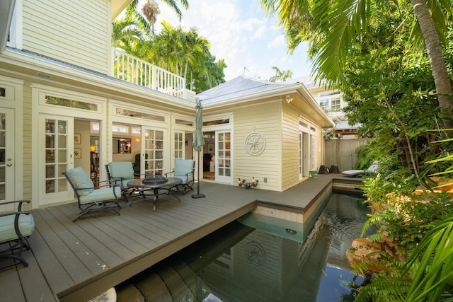 wooden deck with a fenced in pool and french doors