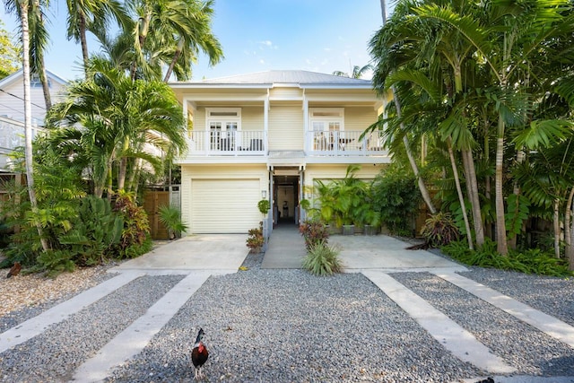 beach home featuring a garage, driveway, metal roof, and a balcony