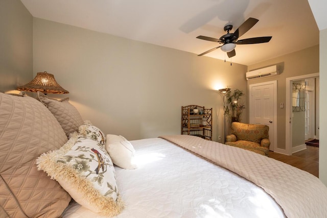 bedroom featuring a wall unit AC, ceiling fan, baseboards, and wood finished floors