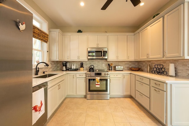 kitchen with light tile patterned floors, stainless steel appliances, tasteful backsplash, light countertops, and a sink