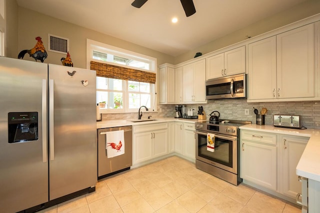 kitchen with tasteful backsplash, stainless steel appliances, a sink, and light countertops