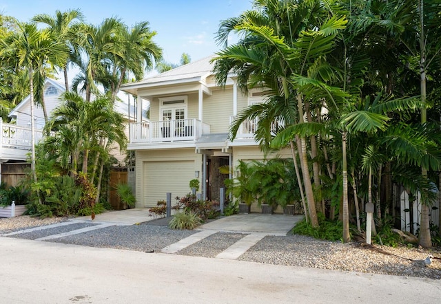 beach home featuring driveway, an attached garage, and a balcony