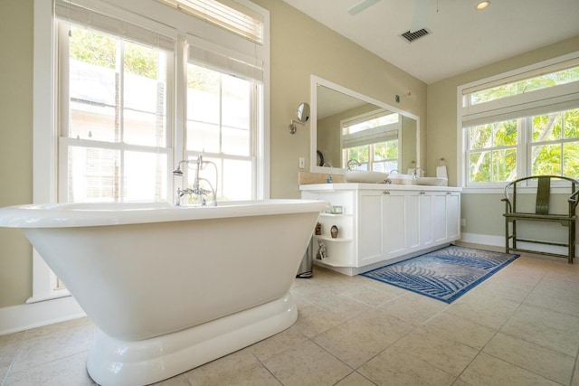 full bath featuring double vanity, baseboards, visible vents, tile patterned flooring, and a freestanding tub