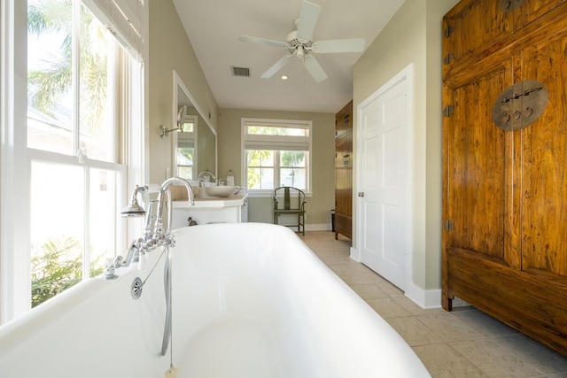 bathroom with a soaking tub, visible vents, ceiling fan, a sink, and tile patterned floors