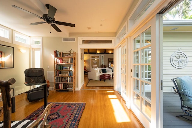 interior space with a ceiling fan, visible vents, and wood finished floors