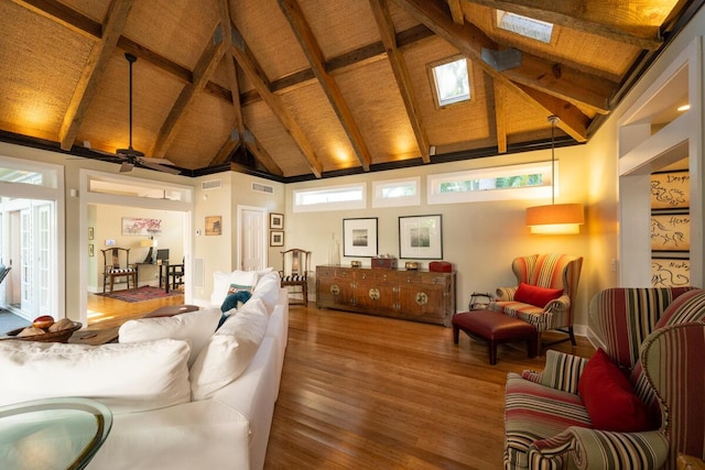 living area with high vaulted ceiling, a skylight, wood finished floors, visible vents, and beamed ceiling