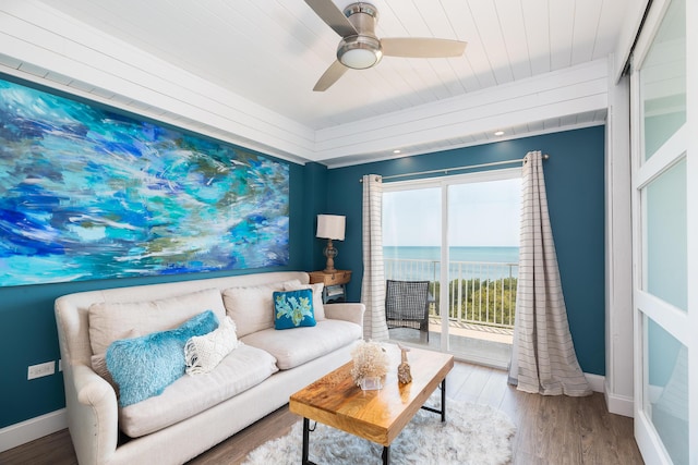 living room with hardwood / wood-style flooring, a water view, and ceiling fan