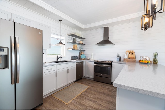 kitchen with sink, white cabinetry, light stone counters, stainless steel appliances, and wall chimney range hood