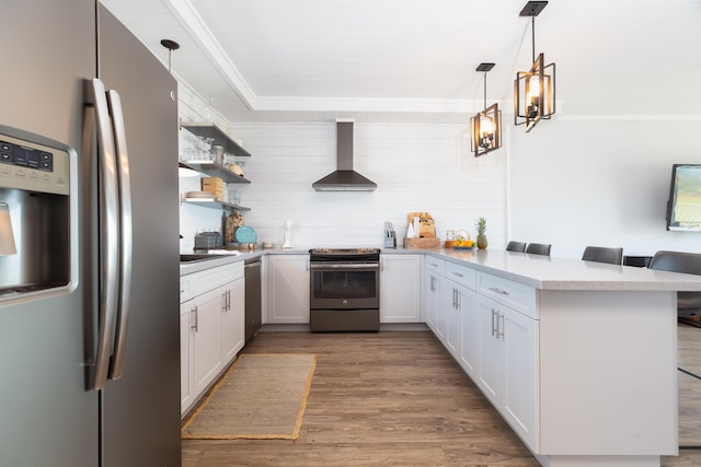 kitchen featuring white cabinets, a kitchen breakfast bar, kitchen peninsula, stainless steel appliances, and wall chimney range hood