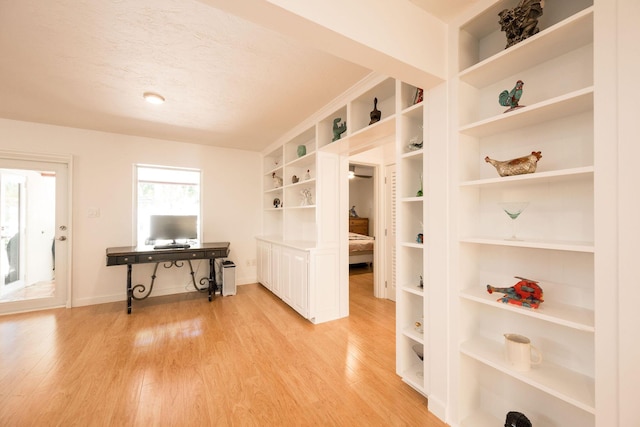 home office featuring light wood-type flooring, a textured ceiling, and baseboards