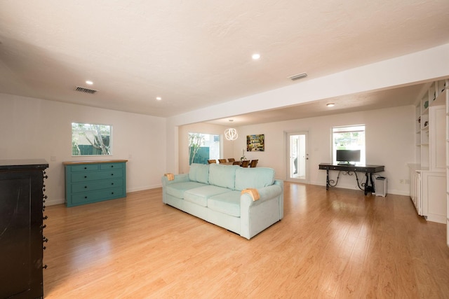 living room featuring light wood-type flooring, visible vents, and baseboards