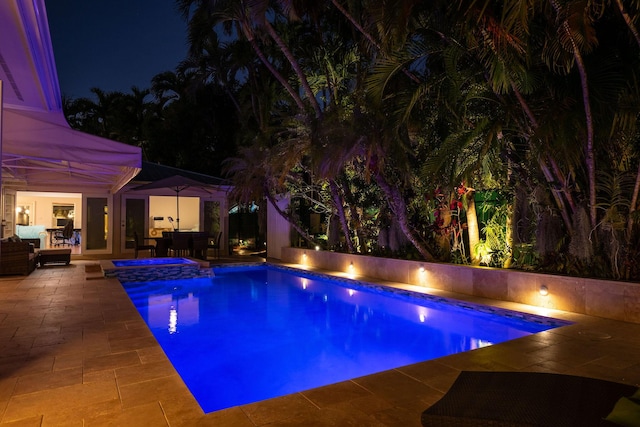 pool at twilight with an outdoor pool, outdoor lounge area, and a patio