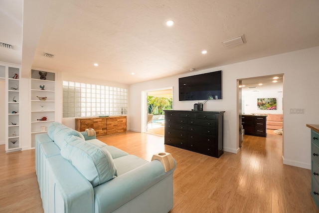 living room featuring light wood-type flooring, visible vents, baseboards, and recessed lighting