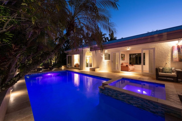 pool at dusk featuring an in ground hot tub, a patio area, and an outdoor pool