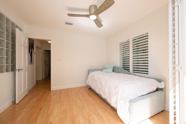 bedroom with light wood-style floors, visible vents, baseboards, and a ceiling fan