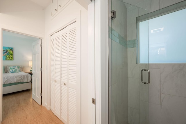 ensuite bathroom with a stall shower, a closet, wood finished floors, and ensuite bathroom