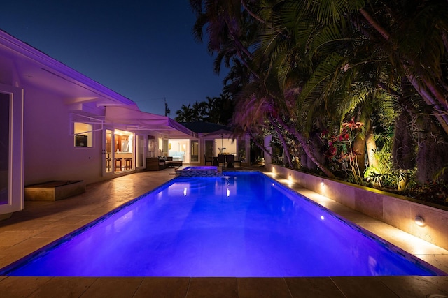 pool at twilight featuring a patio, outdoor lounge area, and an outdoor pool