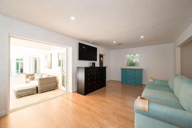 living area with baseboards, light wood finished floors, visible vents, and recessed lighting