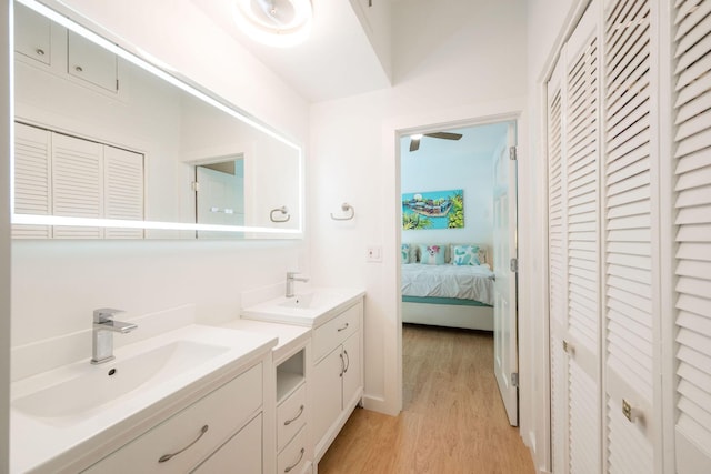 ensuite bathroom with a closet, a sink, and wood finished floors