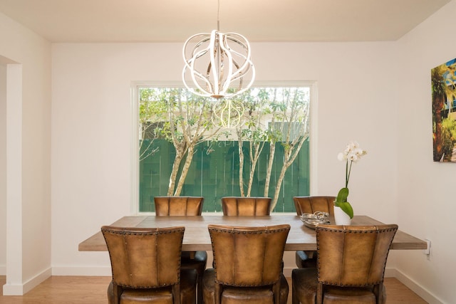 dining area featuring baseboards, a chandelier, and wood finished floors