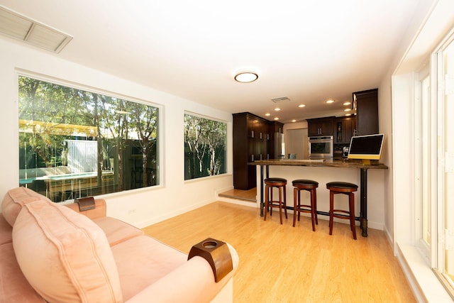 living area featuring light wood-style flooring, plenty of natural light, and visible vents