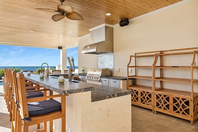 view of patio with grilling area, exterior kitchen, ceiling fan, and a water view