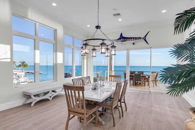 dining space with light hardwood / wood-style flooring, ornamental molding, and a water view