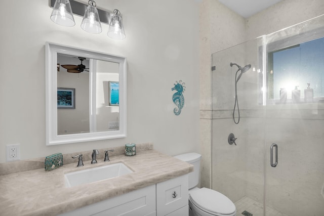 bathroom with vanity, ceiling fan, a shower with shower door, and toilet