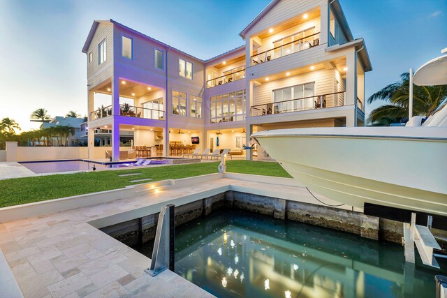 back house at dusk with a balcony and a patio area