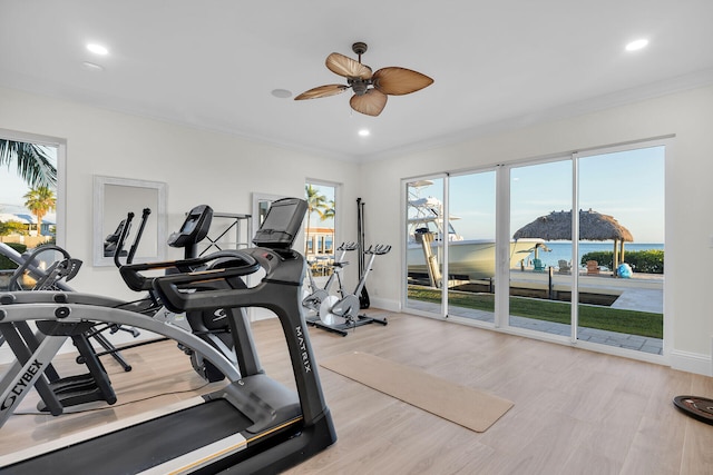 workout room featuring crown molding, a water view, ceiling fan, and light hardwood / wood-style floors