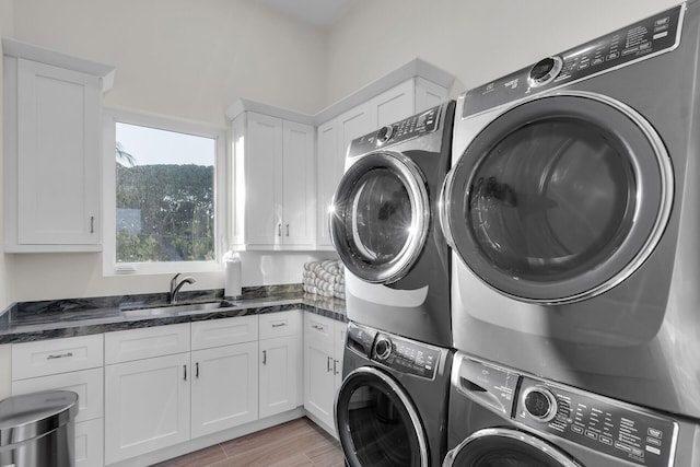 laundry area featuring sink, cabinets, stacked washer / dryer, washer and dryer, and light wood-type flooring