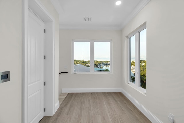 corridor with ornamental molding and light hardwood / wood-style floors