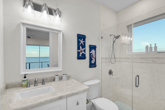 bathroom featuring an enclosed shower, vanity, toilet, and a water view