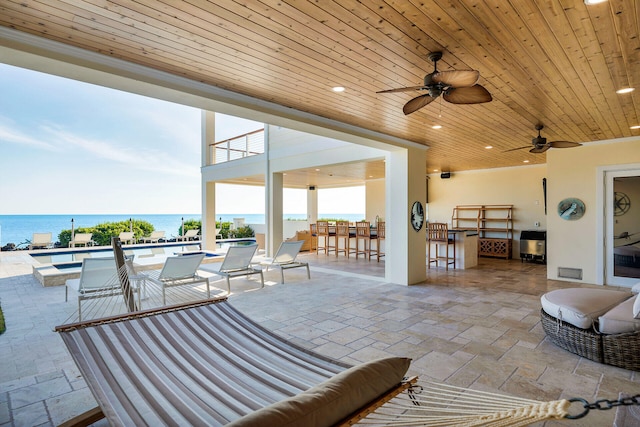 view of patio / terrace with a water view, exterior bar, and ceiling fan