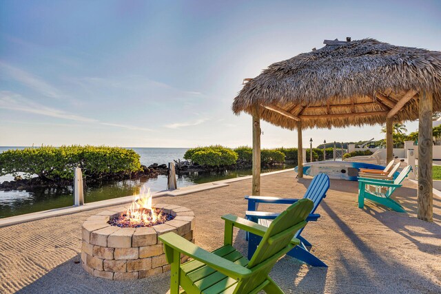 view of community featuring a gazebo, a water view, a patio area, and a fire pit