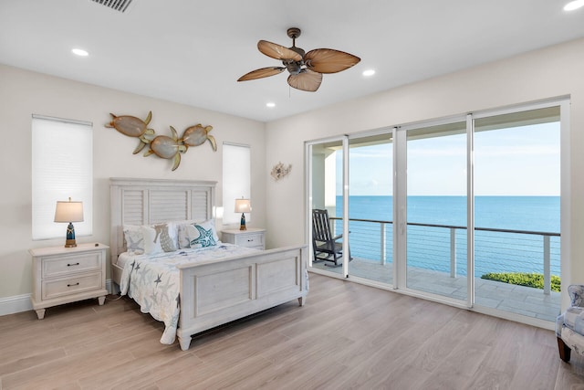 bedroom with a water view, access to exterior, light hardwood / wood-style floors, and multiple windows