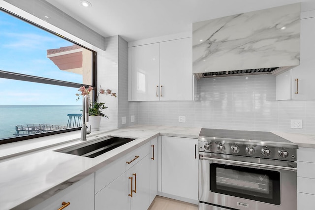 kitchen featuring custom exhaust hood, white cabinets, a water view, stainless steel stove, and backsplash