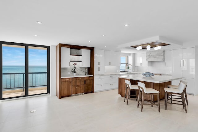 kitchen featuring a kitchen breakfast bar, light countertops, backsplash, white cabinets, and modern cabinets