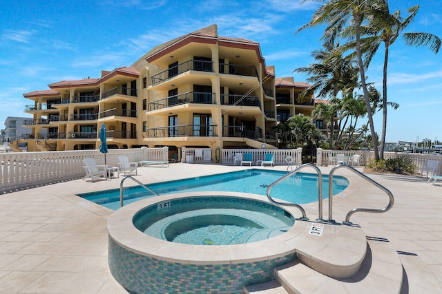 community pool featuring a patio area, fence, and a hot tub