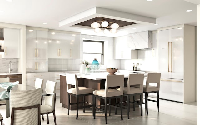 kitchen with modern cabinets, wall chimney range hood, light countertops, built in fridge, and backsplash