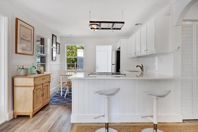 kitchen featuring white cabinetry, a kitchen breakfast bar, kitchen peninsula, and stainless steel refrigerator