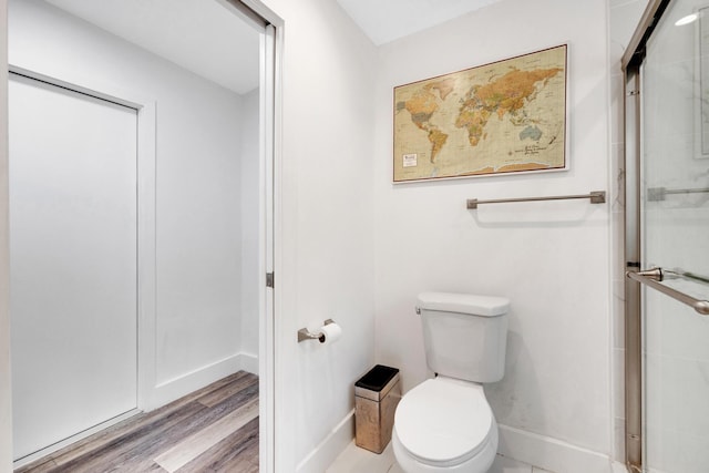 bathroom with an enclosed shower, hardwood / wood-style flooring, and toilet