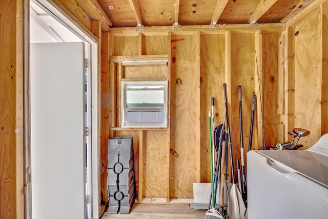 storage room with wood walls, washer / dryer, and light wood-type flooring