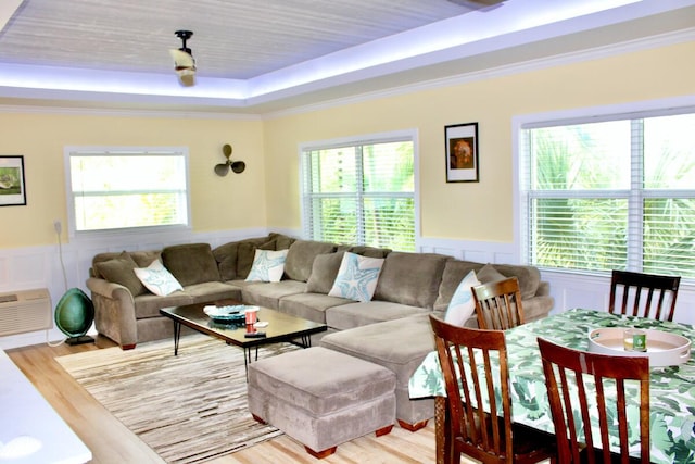 living room featuring light hardwood / wood-style flooring, a tray ceiling, a wealth of natural light, and crown molding