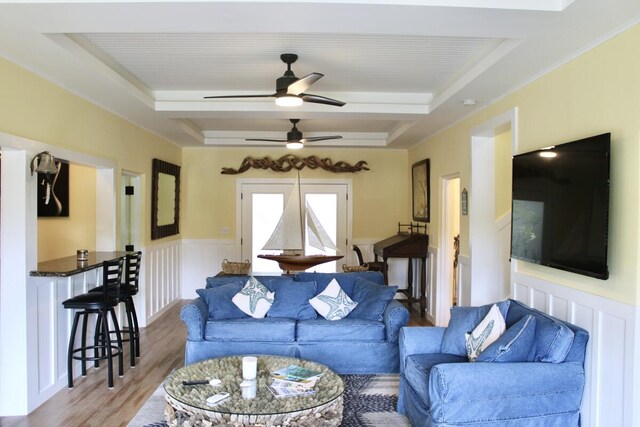 living room with a tray ceiling and wood-type flooring