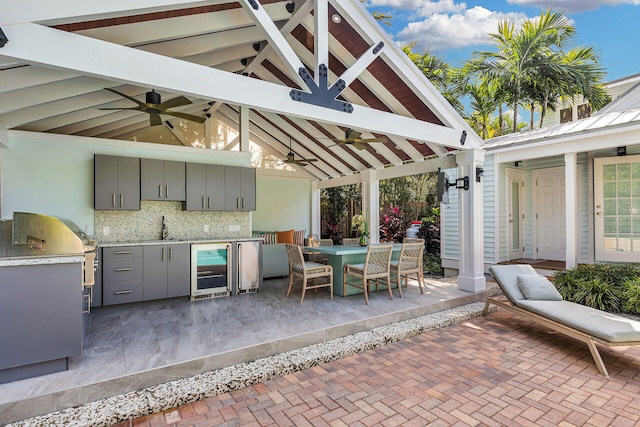 view of patio / terrace with an outdoor kitchen, sink, a gazebo, ceiling fan, and beverage cooler