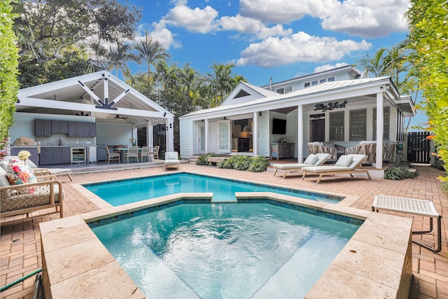 rear view of property featuring an outdoor bar, ceiling fan, a patio area, a pool with hot tub, and area for grilling