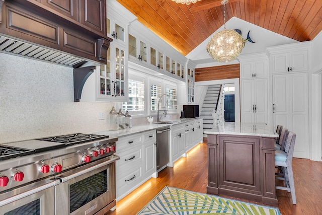 kitchen featuring a kitchen island, appliances with stainless steel finishes, sink, white cabinets, and hanging light fixtures